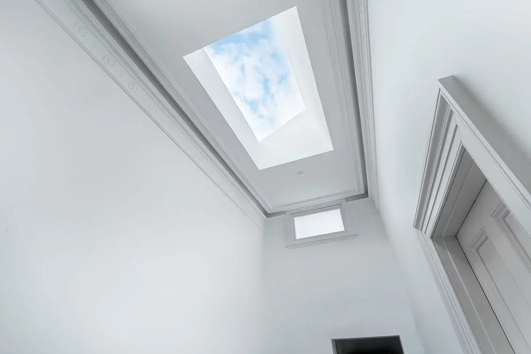 Rectangular skylight bringing daylight into a white hallway